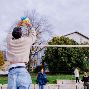 Abbildung einer Gruppe Bewohner, die zusammen Volleyball spielt