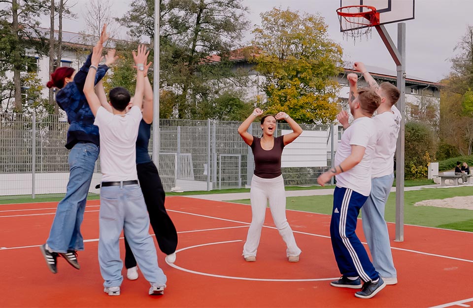 Abbildung einer Gruppe jubelnder Jugendlicher auf einem Basketballplatz