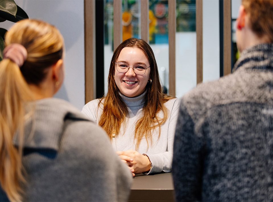 Image of a receptionist welcoming two guests