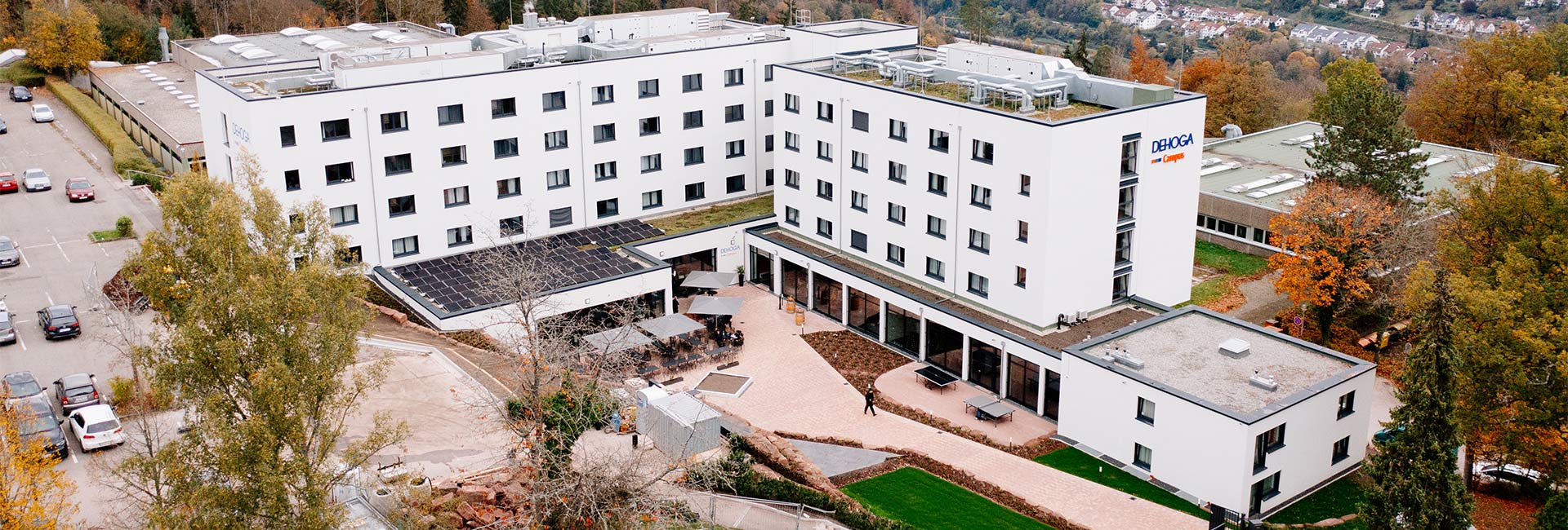 Bird's eye view of two campus buildings in front of a mixed forest