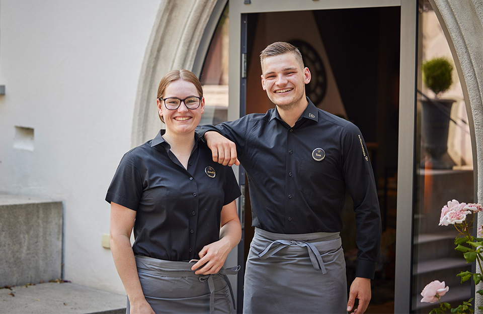 Abbildung zweier Auszubildenden in Angestellten-Uniformen aus dem Gastgewerbe